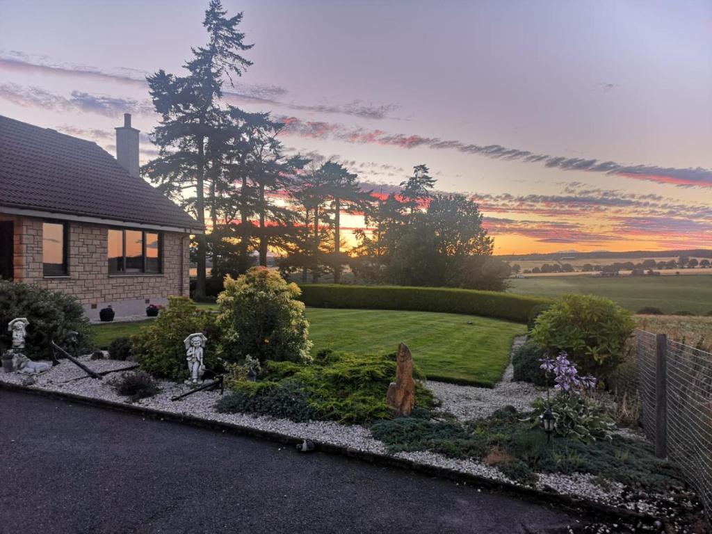 a house with a garden in front of a sunset at Hillhaven Bed &Breakfast in Fortrose