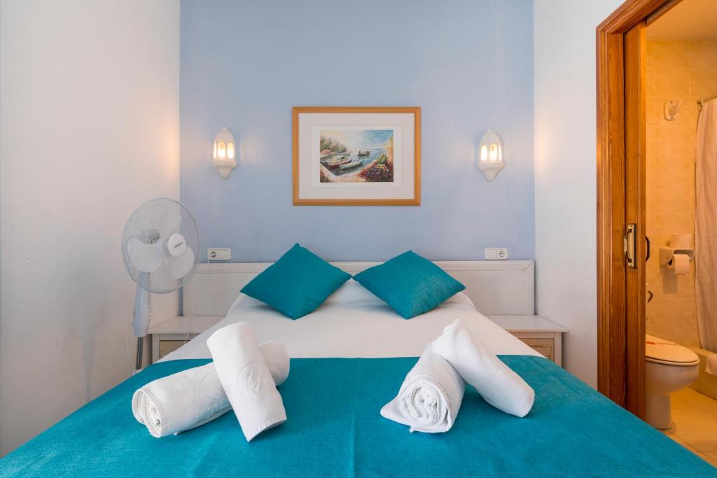 a bedroom with a blue and white bed with towels at Hostal Ferrer in San Antonio
