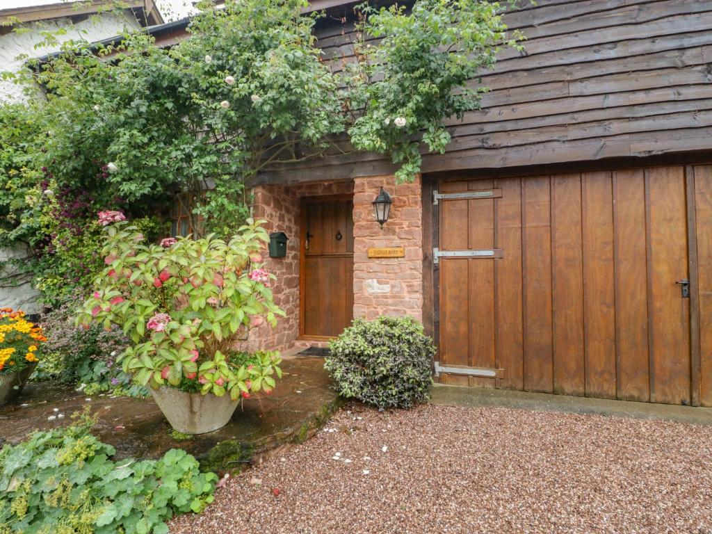 a garage with a wooden door and some plants at Flora's Barn in Taunton