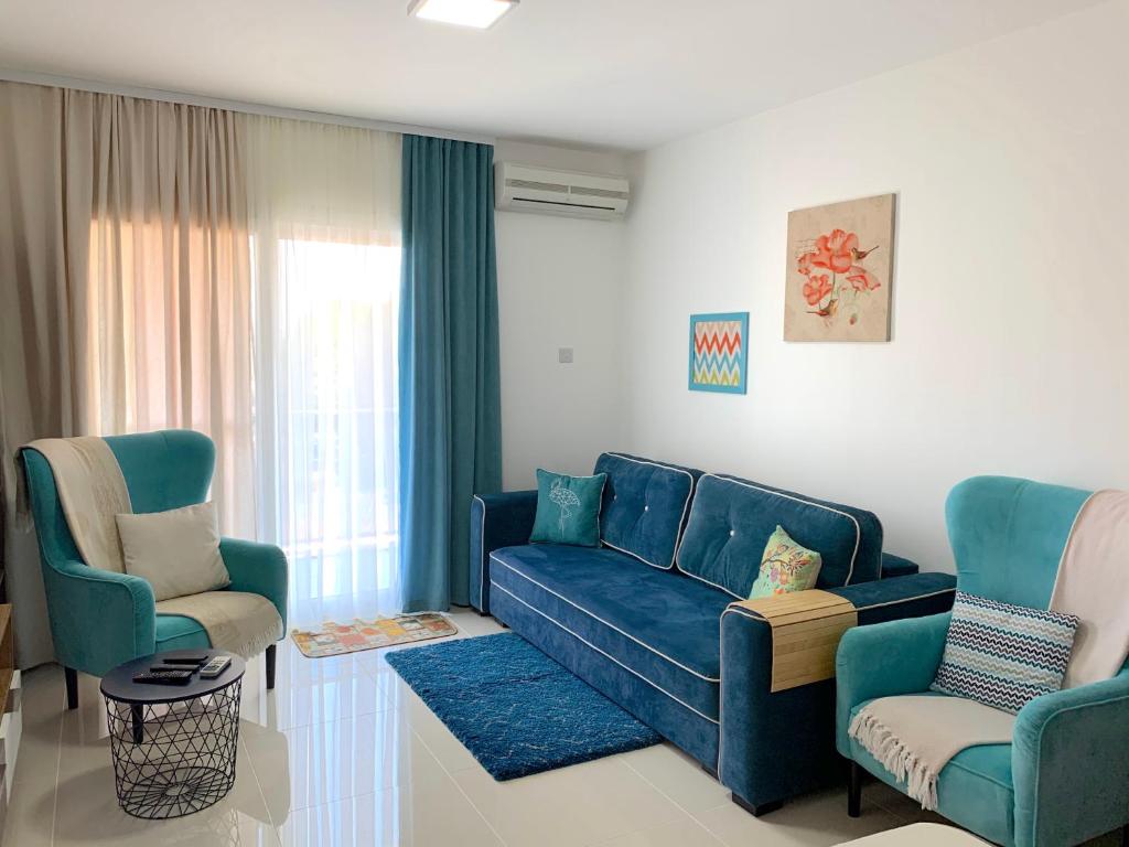 a living room with a blue couch and two chairs at Tatli Apartment in Famagusta