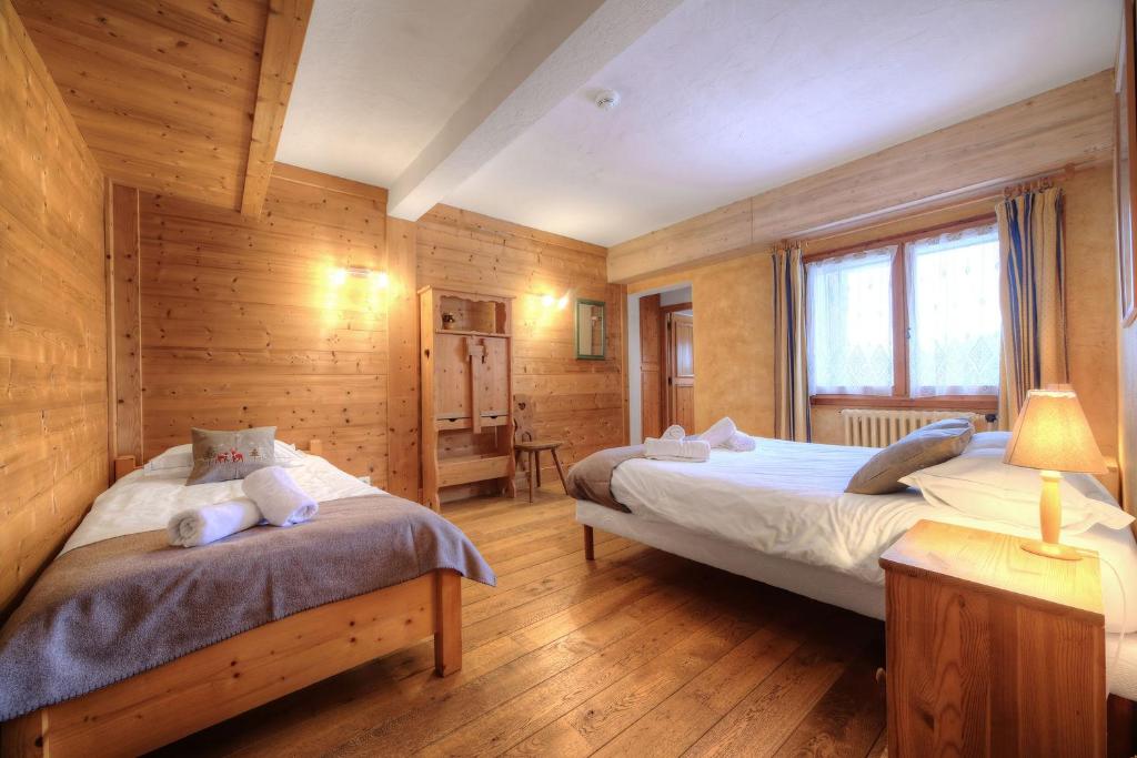 two beds in a room with wooden walls at Chalet-Hôtel de l&#39;Etape in Les Contamines-Montjoie
