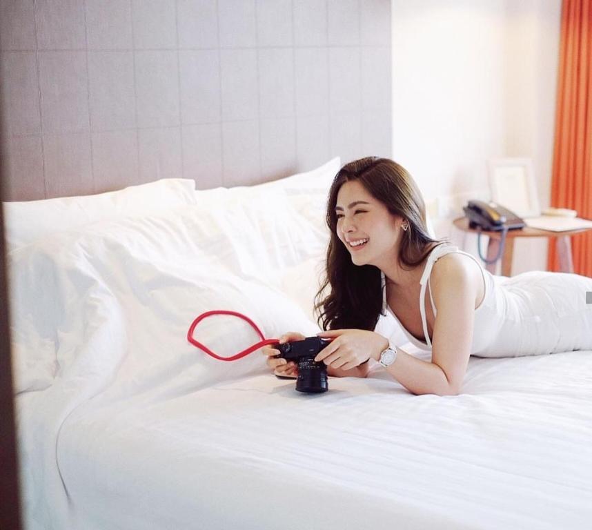a woman holding a white tennis racket on top of a bed at Manita Boutique Hotel in Pattaya South