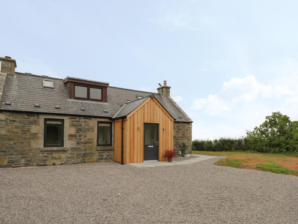 an old stone house with a large driveway at Enzie Station Cottage in Buckie