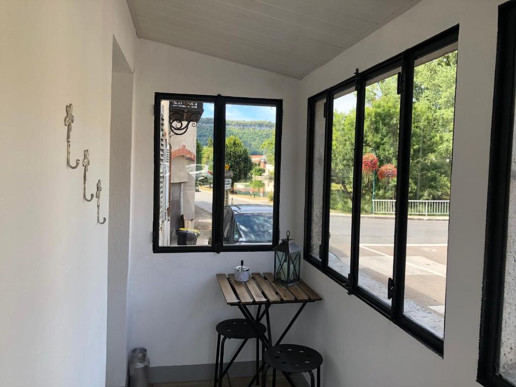 Pokój z oknami, stołem i 2 stołkami w obiekcie le petit champliman w mieście Ornans