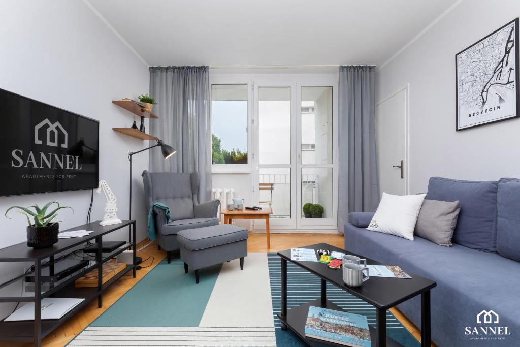 uma sala de estar com um sofá azul e uma cadeira em Apartament Gryf Szczecin em Szczecin