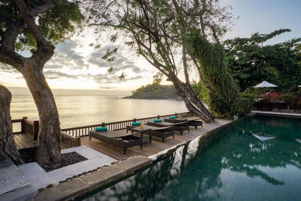 una piscina con bancos y vistas al agua en Mimpi Resort Tulamben, en Tulamben