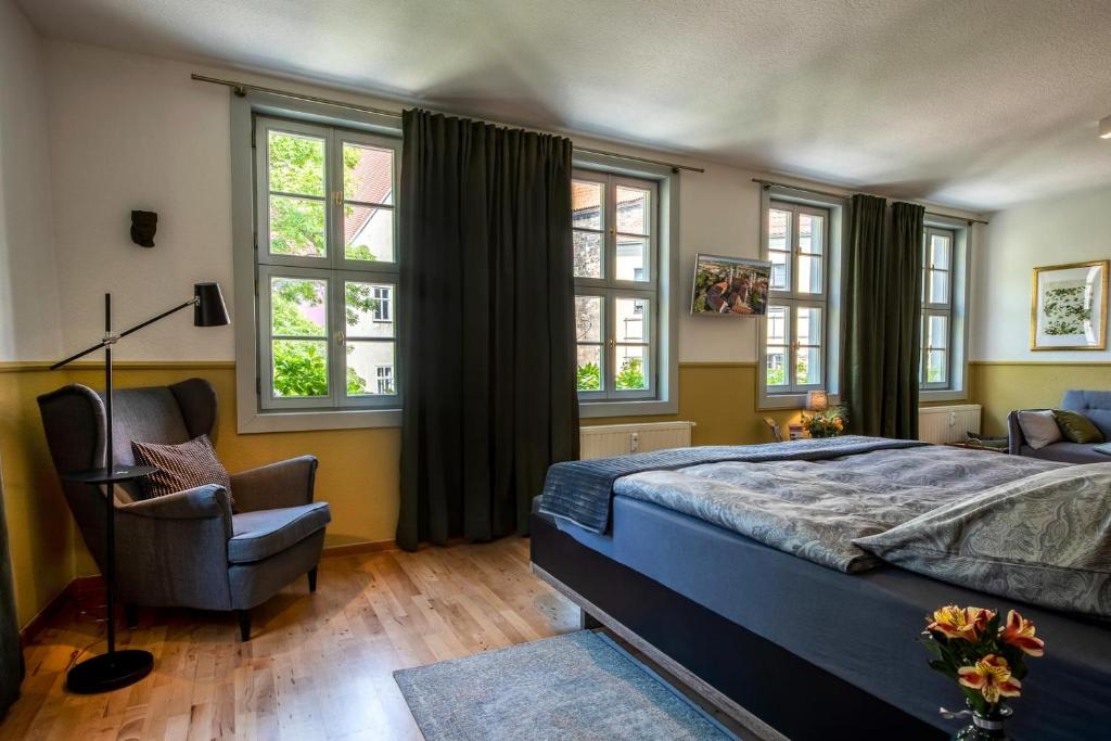 a bedroom with a bed and a chair and windows at Ferienwohnung am Dom in Naumburg