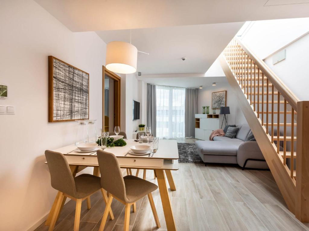 a dining room and living room with a table and chairs at VacationClub – Seaside Park Penthouse 608 in Kołobrzeg