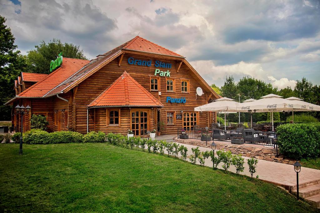 a large wooden building with a restaurant in front of it at Grand Slam Park Inn in Budapest