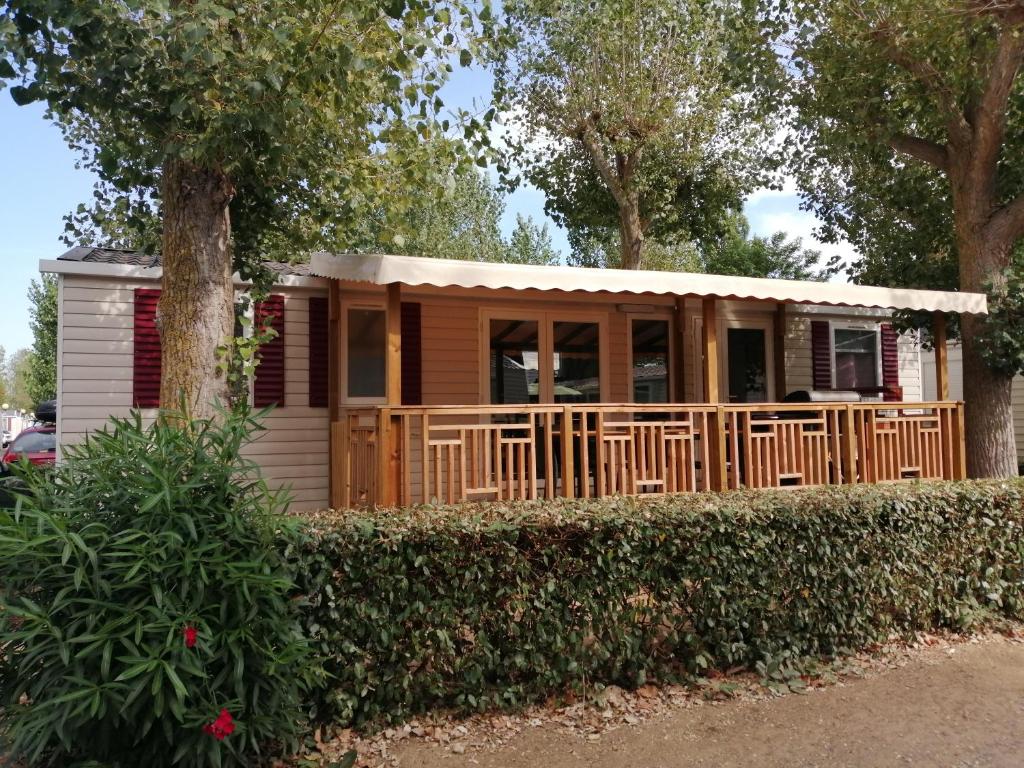 een tiny house met een veranda en een boom bij Mobil home La Mer in Vias