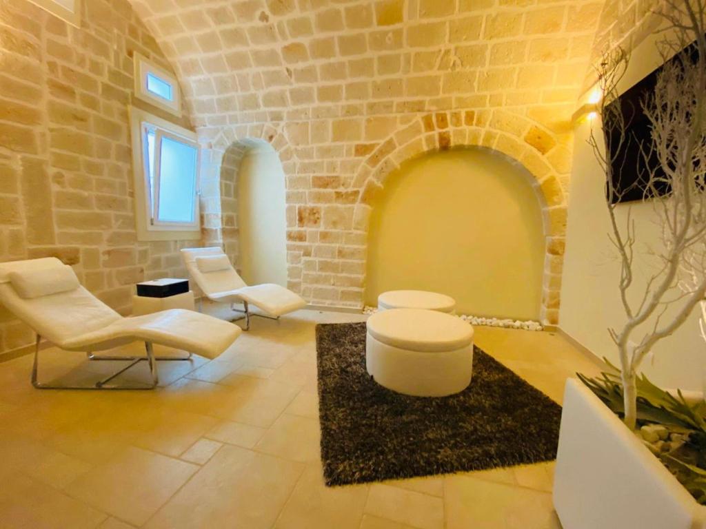 ein Wohnzimmer mit weißen Stühlen und einer Ziegelwand in der Unterkunft Vacanze in Puglia Monopoli in Monopoli