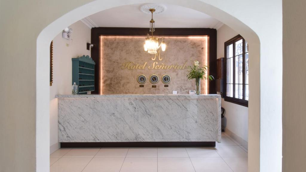 a lobby with a marble counter with a chandelier at Hotel Señorial in Lima