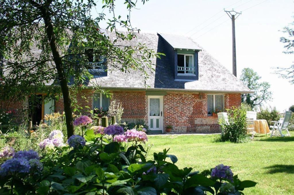 une maison en briques avec des fleurs dans la cour dans l'établissement La chaumière, à Heuland