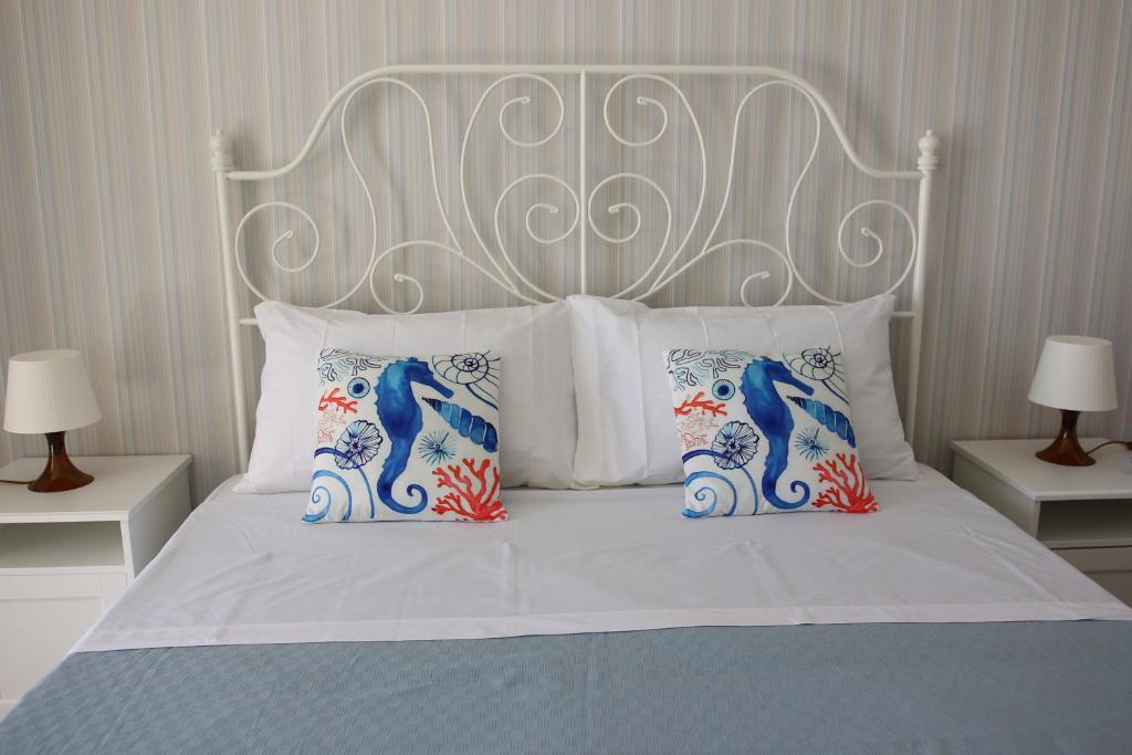 a bed with a white headboard and two pillows at Residence La Perla Marzamemi in Pachino
