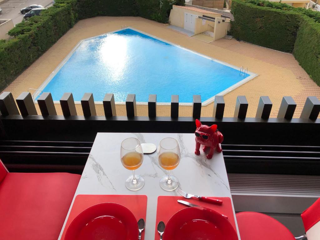 a table with two glasses of wine next to a swimming pool at Rez de jardin OU ascenseur 4 ieme PISCINE -WIFI-Village naturiste holidaysochic in Cap d'Agde
