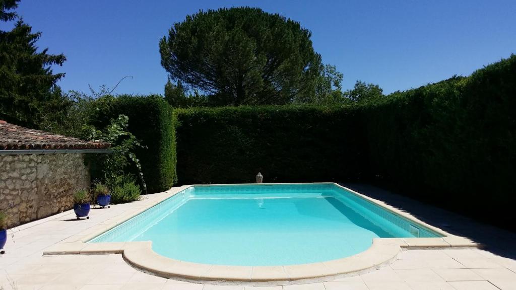 uma piscina num quintal com uma sebe em Sur mon chemin chambres d'hôtes em Cahuzac-sur-Vère