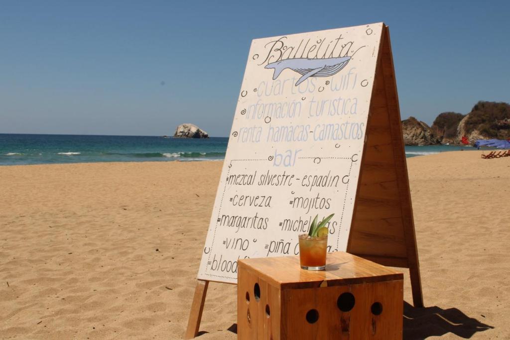 un cartel en la playa con una bebida en una caja en Ballelita, en Zipolite