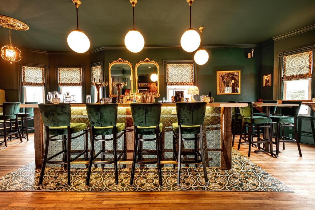 a bar in a room with green bar stools at Slaymaker & Nichols Gastro House & Inn in Charlottetown