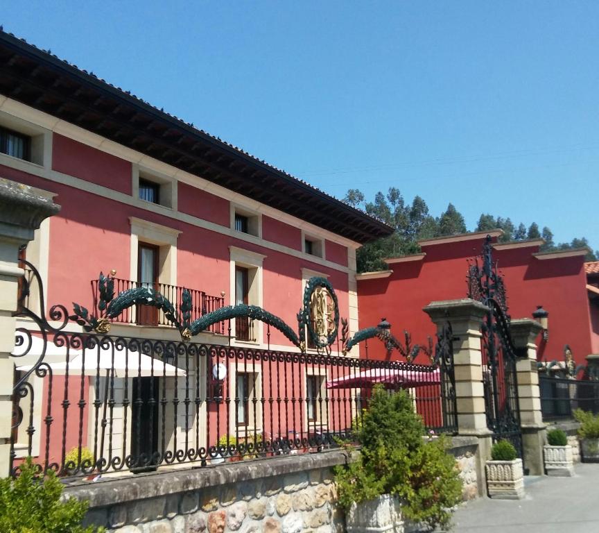 un edificio rojo con una valla delante en Posada Santa Eulalia en Villanueva de la Peña