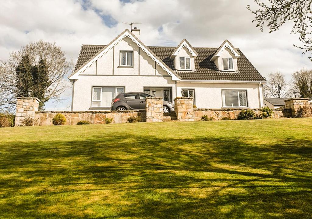 una casa bianca con una macchina parcheggiata nel cortile di Moat Holiday Rental a Lisnaskea