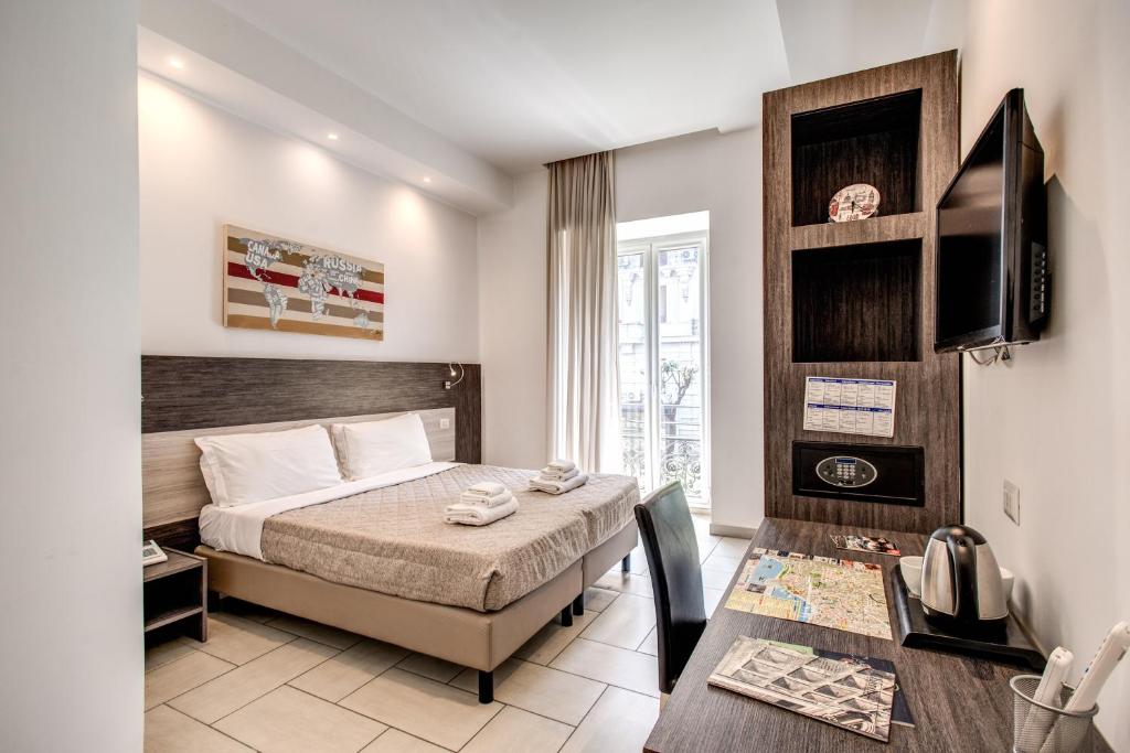 1 dormitorio con cama, mesa y TV en Napoli Suite, en Nápoles