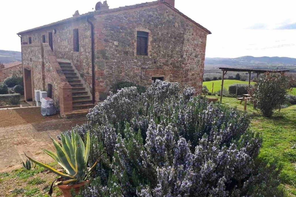 un antiguo edificio de piedra con flores púrpuras delante de él en Casetta Tre Poderi appartamento Papaveri, en Monte Cucco