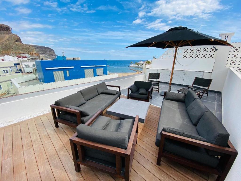 a patio with a couch and a table and an umbrella at luxury penthouse with ocean and beach views in Puerto de Mogan in Puerto de Mogán