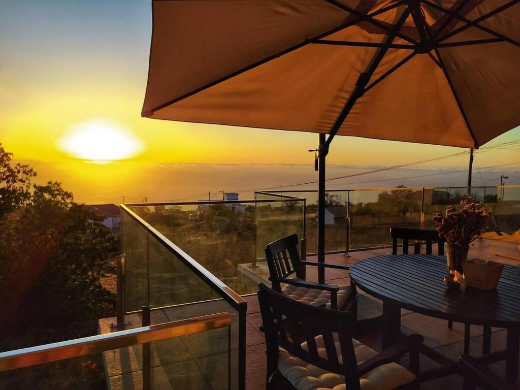 a table with an umbrella on a balcony with the sunset at Casa El Peral in Puntagorda