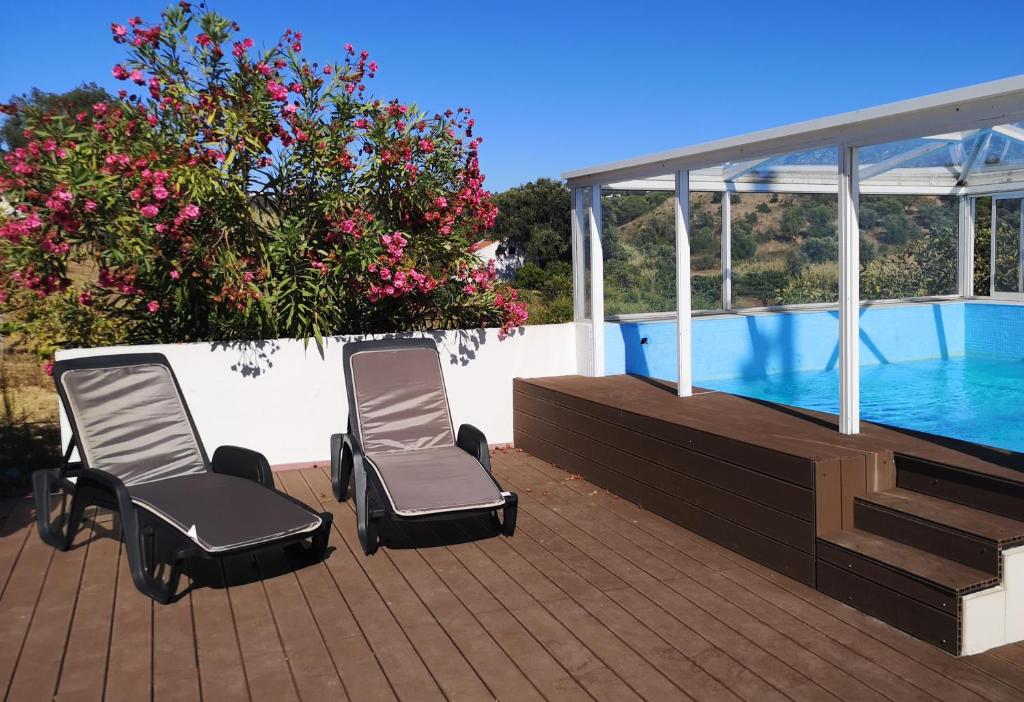 two chairs sitting on a deck next to a swimming pool at Monte do Parral in Santiago do Cacém