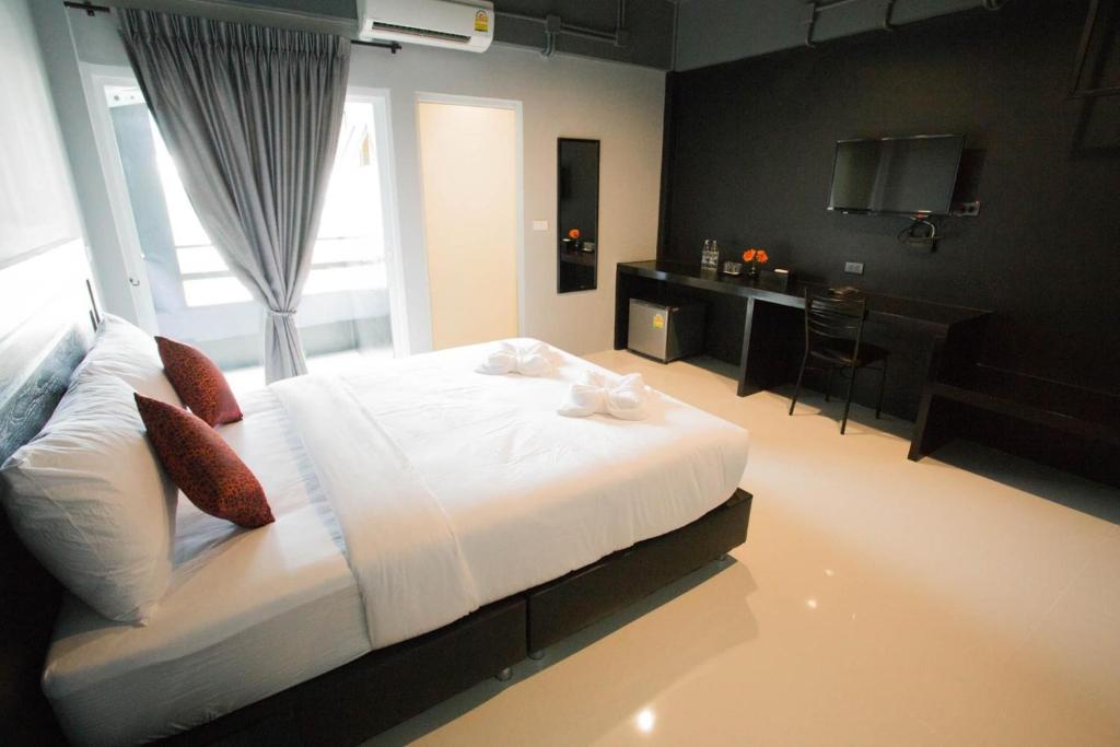 1 dormitorio con 1 cama blanca grande y escritorio en B-Black Hotel Chonburi, en Chonburi