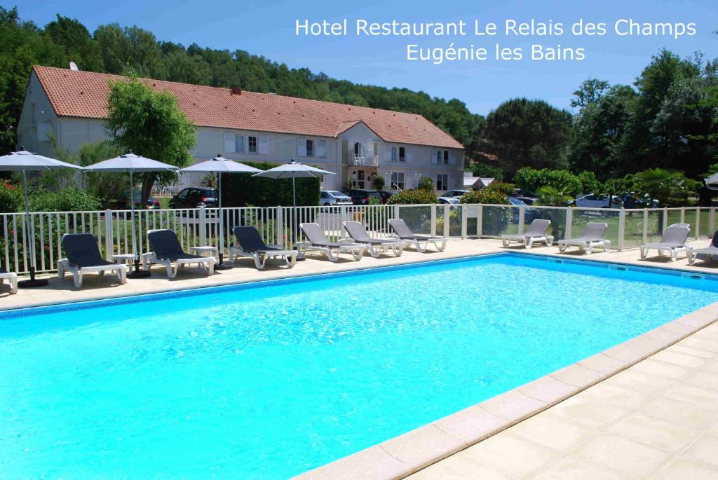 a large swimming pool with chairs and umbrellas at Hotel Le Relais des Champs in Eugénie-les-Bains