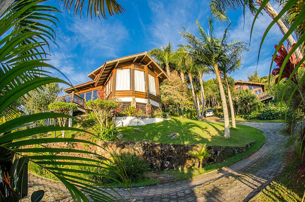 uma casa com uma palmeira em frente em Pousada Moradas da Silveira em Garopaba