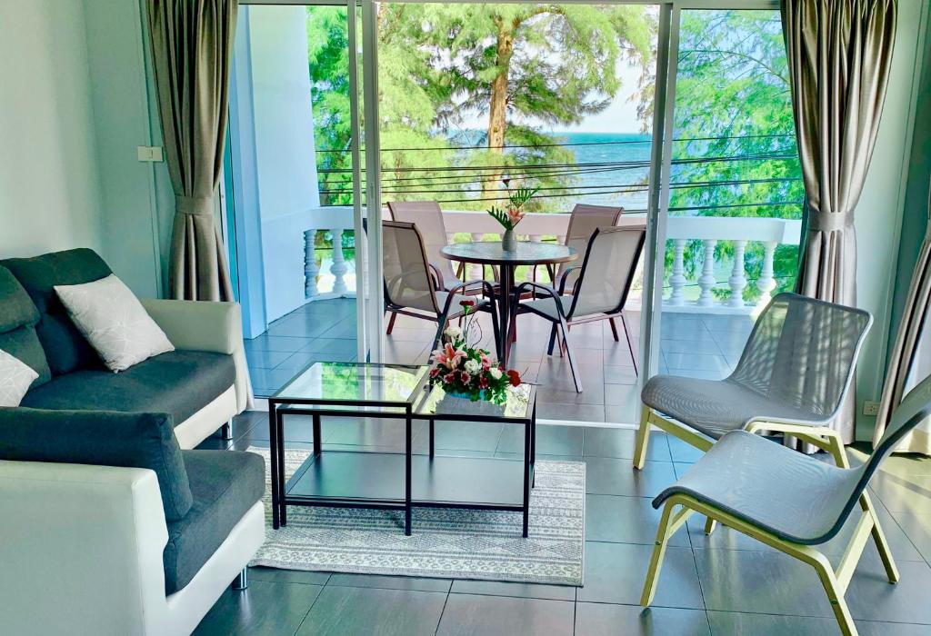 een woonkamer met een bank en een tafel en stoelen bij THE BEACH CHA AM Suites in Cha Am