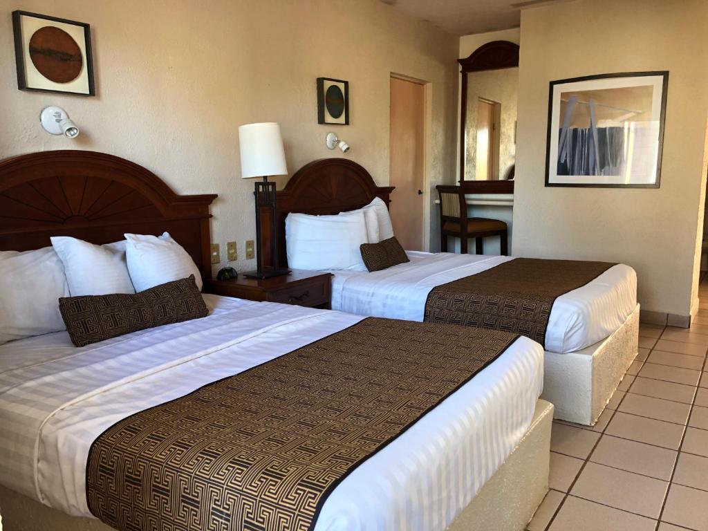 um quarto de hotel com duas camas e uma mesa em Hotel Hacienda Tetakawi em San Carlos