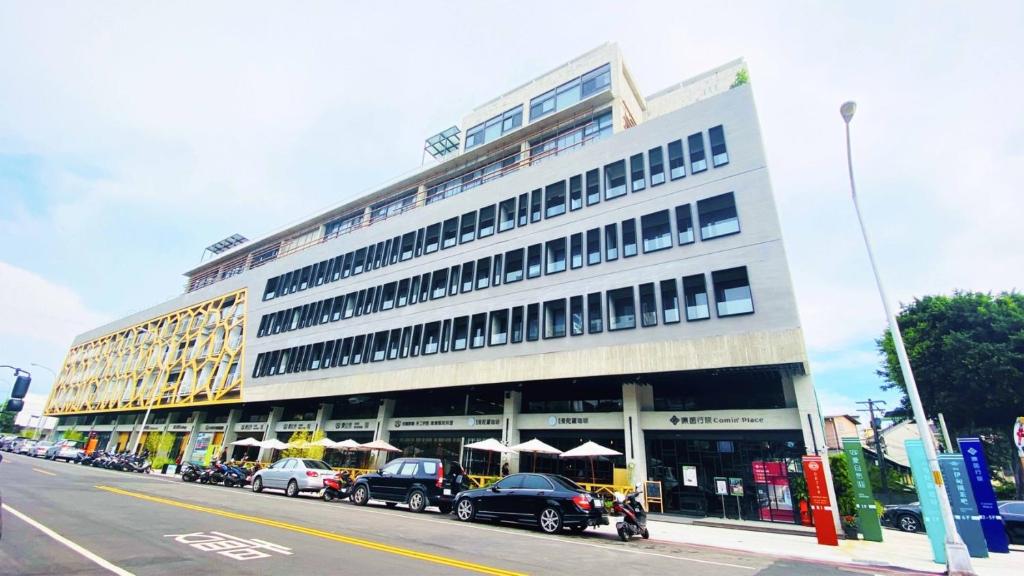a large building with cars parked in front of it at Comin' Place in Wuri