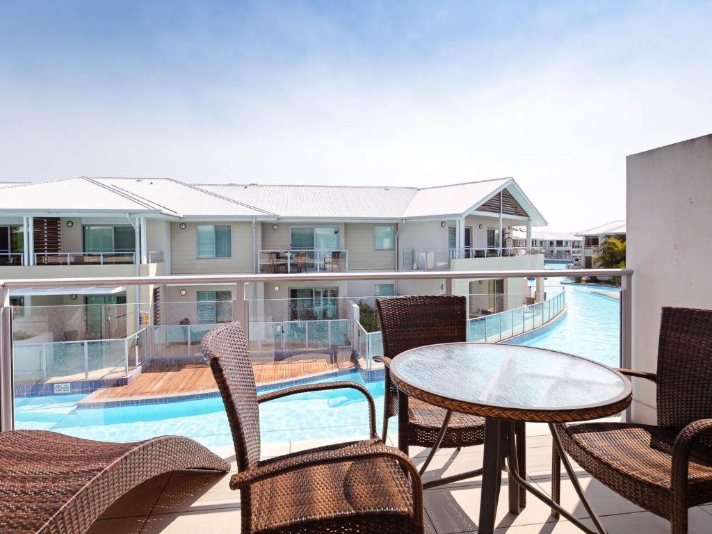 a balcony with a table and chairs and a pool at Pacific Blue 245-265 Sandy Point Rd - Dual Key Access, air conditioned unit with resort facilities and linen supplied in Salamander Bay