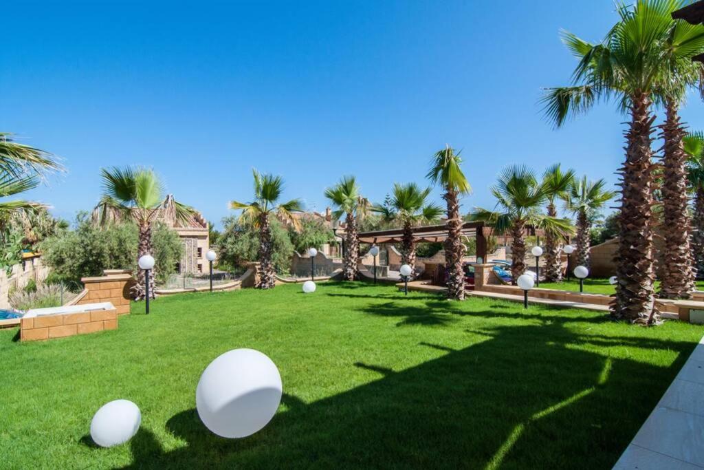 a yard with palm trees and white eggs on the grass at Baia degli Emiri in Lascari