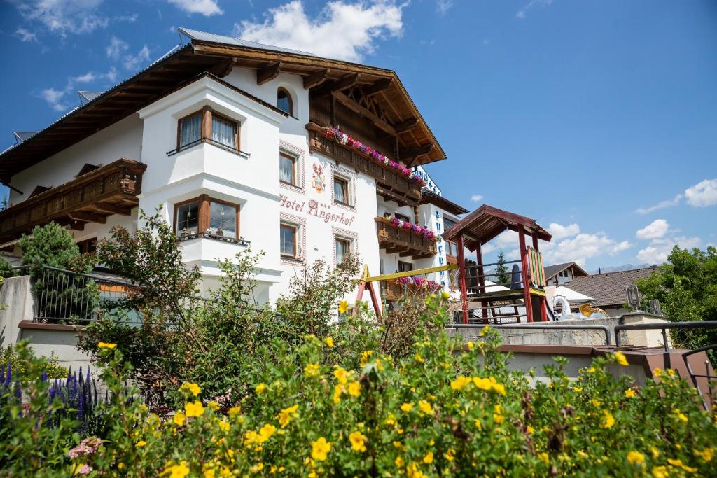 a white house with flowers in front of it at Ferienhotel Angerhof in Fiss