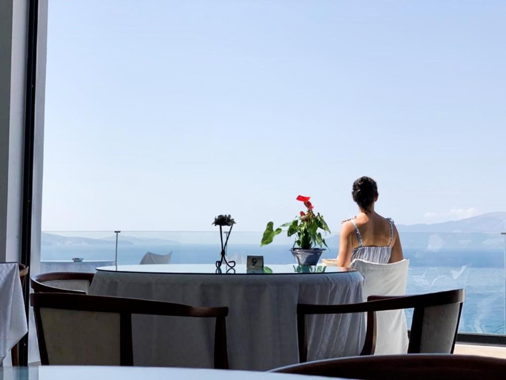 a woman sitting at a table with a plate of food at Olympia Hotel in Sarandë