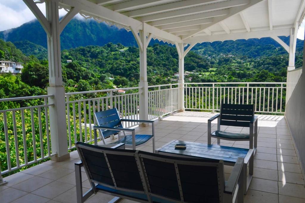 a porch with chairs and a table with a view at Le Colibri Vert in Le Morne-Vert