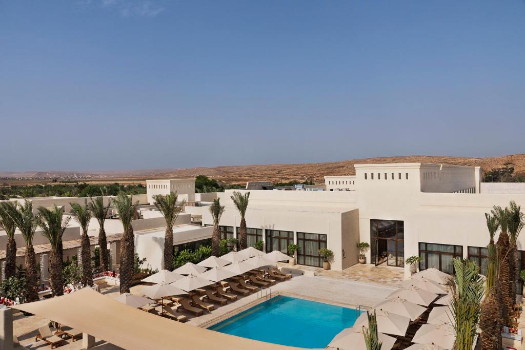 een uitzicht op een resort met een zwembad en palmbomen bij Kedma by Isrotel Design in Sede Boqer