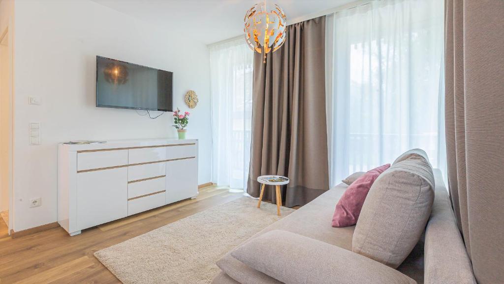 ein Wohnzimmer mit einem Sofa und einem TV in der Unterkunft Alpine Appartement Top 2 by AA Holiday Homes in Tauplitz