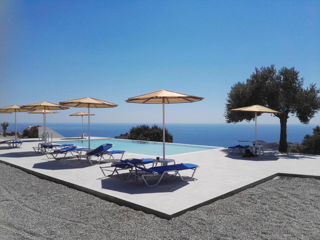 a group of chairs and umbrellas next to a pool at Bouganville Bed & Breakfast Stegna in Archangelos