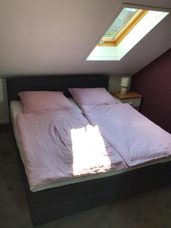 Apartment am Park -Calluna في شنيفردينغين: سرير بملاءات وردية ونافذة في غرفة