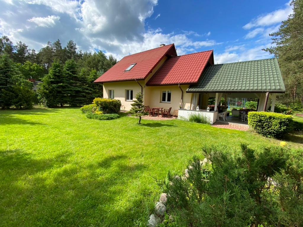 dom z czerwonym dachem na zielonym podwórku w obiekcie Willa Boho Cudo w mieście Cieksyn