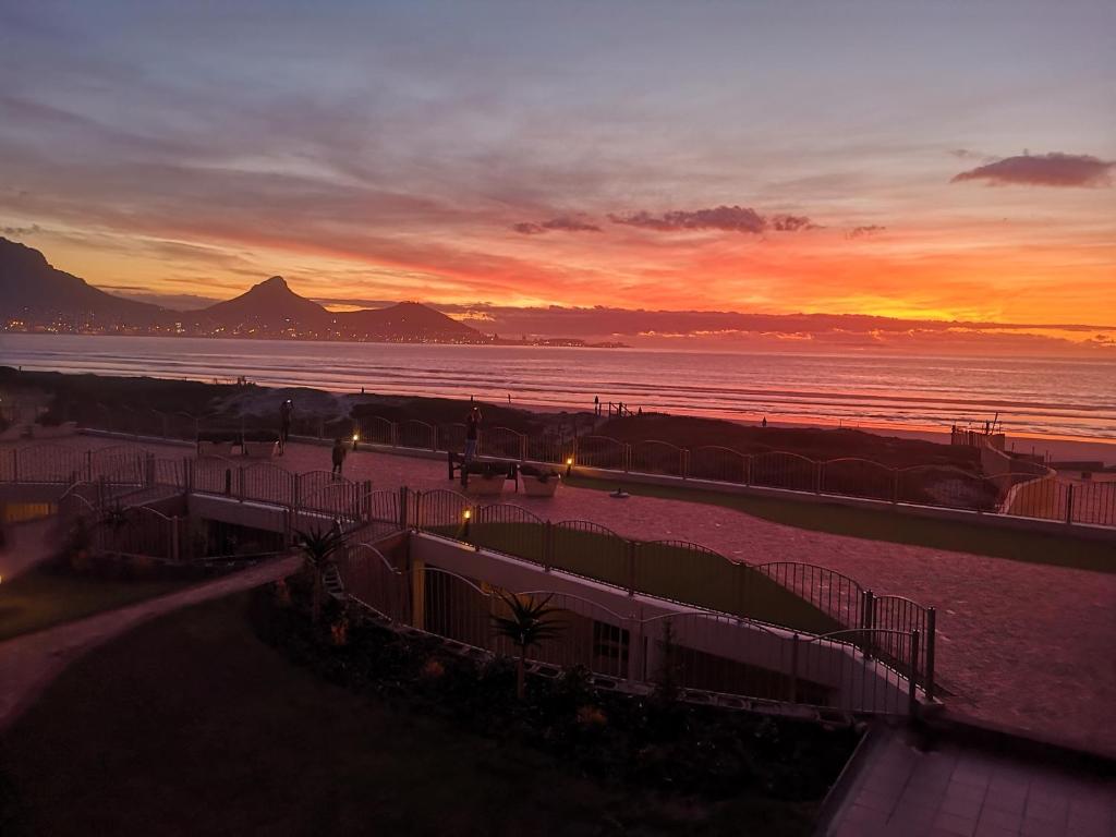 a view of a beach at sunset with the ocean at Lagoon Beach Neptune Isle Cape Town in Cape Town