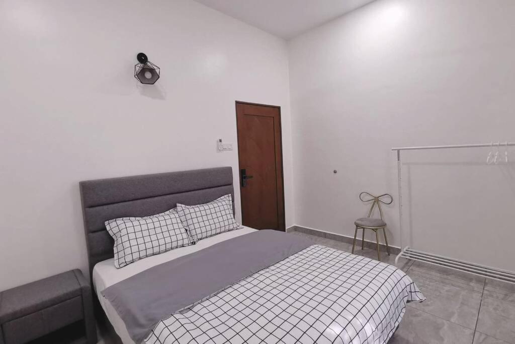 a white bedroom with a bed with a gray headboard at Stay Inn Sikamat (Seremban Homestay) in Seremban