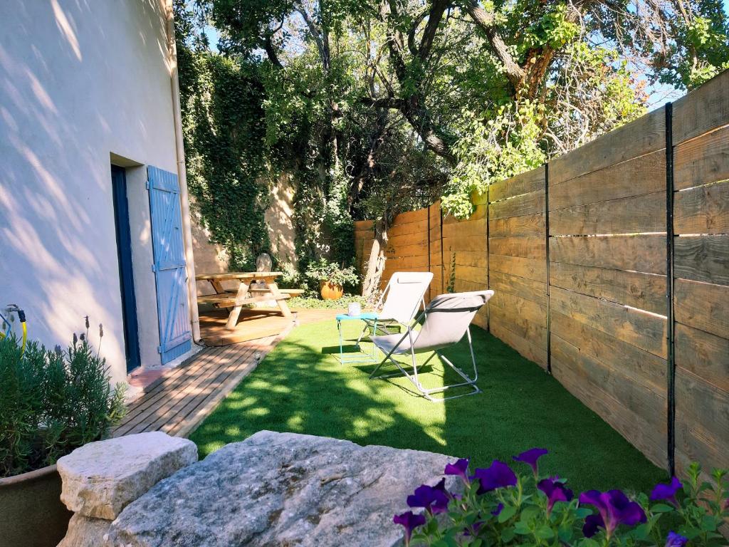 a garden with a chair and a table and a fence at Gîte La Quille - Maison de hameau en Provence pour 4 personnes avec jardin privatif in Le Puy-Sainte-Réparade