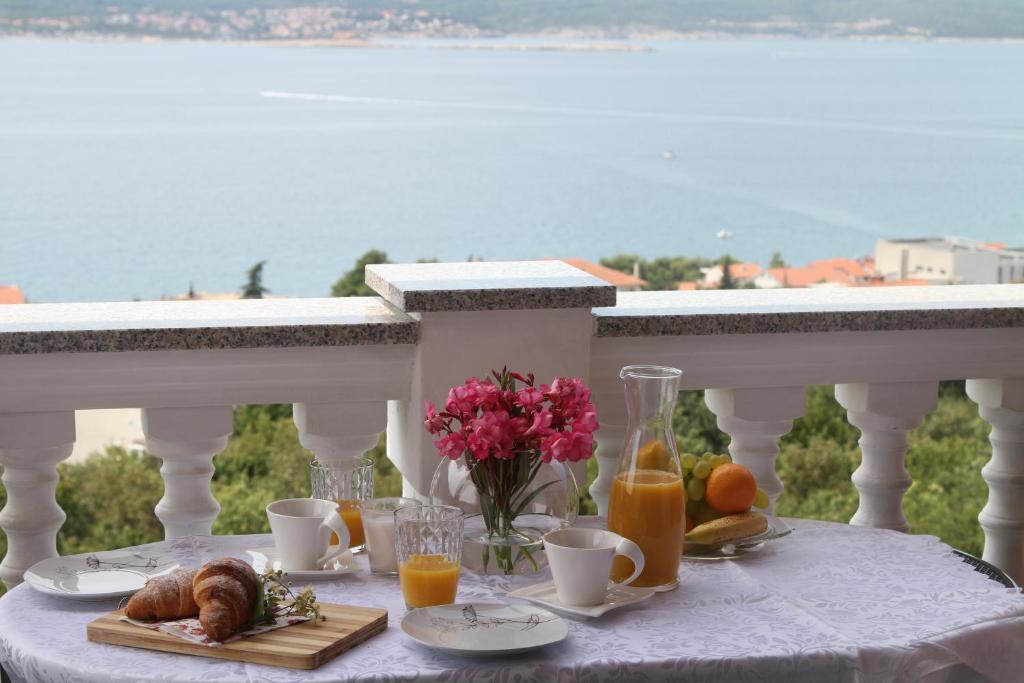 a table with breakfast foods and orange juice on a balcony at Apartments Karalic in Crikvenica