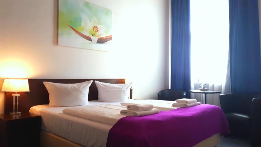 a hotel room with a bed with towels on it at Hotelpension Margrit in Berlin